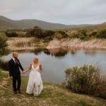 Bride and groom walking next to dam